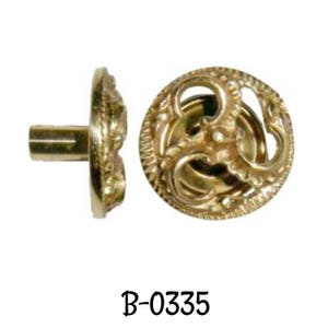 May include: A gold-toned metal knob with a decorative, ornate design. The knob has a round base and a short, cylindrical stem. The knob is labeled "B-0335".