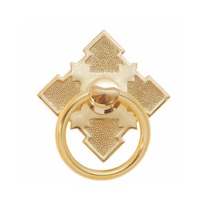 May include: A gold-toned, ornate, diamond-shaped pull with a ring handle. The pull has a textured surface and a geometric design.