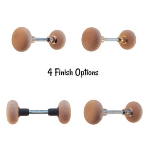 May include: Four different finishes of a wooden knob with a metal rod. The knob is round and has a wood grain texture. The rod is silver, black, or gold.