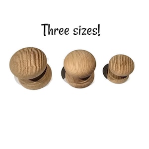 May include: Three wooden knobs in varying sizes are displayed against a white background. The knobs have a rounded top and a cylindrical base. The text "Three sizes!" is written above the knobs in a handwritten style.