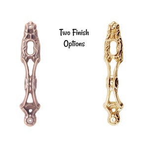 May include: Two ornate metal keyhole escutcheons, one in a brass finish and one in an antique brass finish.  Two Finish Options.