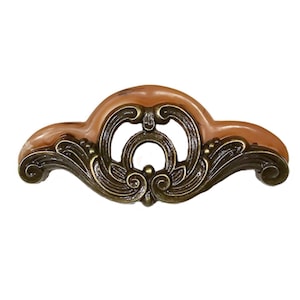 May include: An ornate cabinet pull with a brown and bronze finish. The pull features a central open design with swirling details and a curved shape, suitable for furniture restoration or decorative projects.