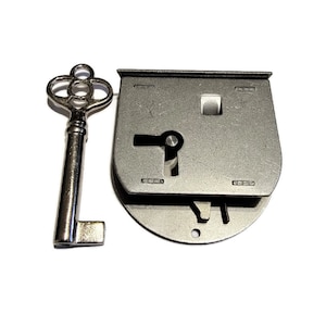 May include: A silver key with a decorative head and a silver lock with a keyhole and a lever. The lock is attached to a metal plate.