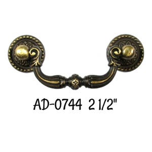 May include: A 2 1/2 inch antique brass cabinet pull with a decorative scroll design. The pull is labeled "AD-0744 2 1/2"".