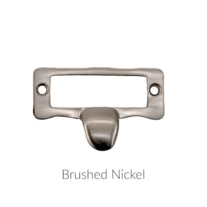 May include: Brushed nickel drawer pull with a rectangular label holder.