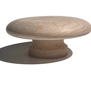 May include: A light-colored wooden cabinet knob with a rounded top and a short, cylindrical base. The knob is made of unfinished wood, showcasing the natural grain and texture. The knob is designed for use on drawers or cabinets.