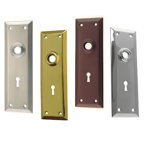 May include: Four door hardware plates in different finishes: brushed nickel, brass, oil rubbed bronze, and polished chrome. Each plate has a keyhole and a round hole for a door knob.