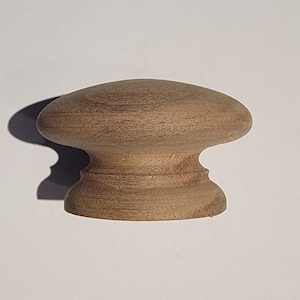 May include: A wooden knob with a rounded top and a slightly flared base. The knob is a light brown color and has a smooth, polished finish.