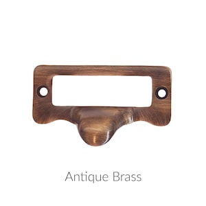 May include: Antique brass drawer pull with a rectangular label holder.