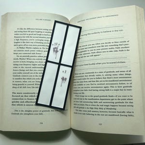 May include: A black and white bookmark with a quote about gratitude from the book "You Are a Badass" by Jen Sincero. The bookmark features a handprint design.