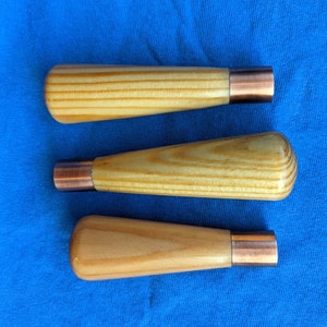 May include: Three wooden tools with copper-colored metal tips. The tools are on a blue fabric background.