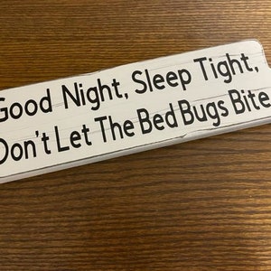 May include: White wooden sign with black text that reads "Good Night, Sleep Tight, Don't Let The Bed Bugs Bite".