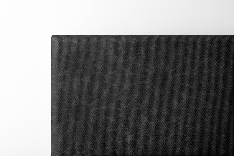May include: Close-up of a black headboard with a textured fabric. The fabric has a subtle pattern of small, irregular shapes.