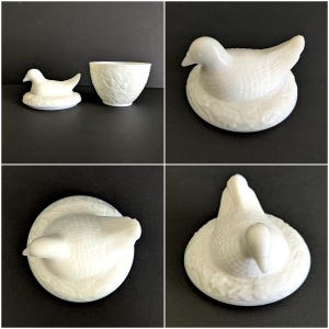 Puede incluir: Figura de paloma de cer&aacute;mica blanca sobre un nido, con un cuenco peque&ntilde;o a juego. La paloma tiene texturas de plumas detalladas y est&aacute; posada en un nido detallado. El cuenco tiene un patr&oacute;n de hojas. Los art&iacute;culos se muestran sobre una superficie negra.