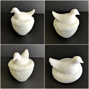 Puede incluir: Figura de paloma de cer&aacute;mica blanca posada sobre un recipiente en forma de nido. La paloma tiene texturas de plumas detalladas, y el nido presenta un patr&oacute;n floral. Es probable que sea un objeto decorativo o una caja de baratijas.