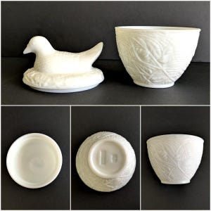 Puede incluir: Una figura de pato de cer&aacute;mica blanca sobre un nido y un cuenco de cer&aacute;mica blanca con un patr&oacute;n de hojas. El pato est&aacute; detallado con plumas. El cuenco tiene una superficie texturizada. La base del cuenco tiene un sello.