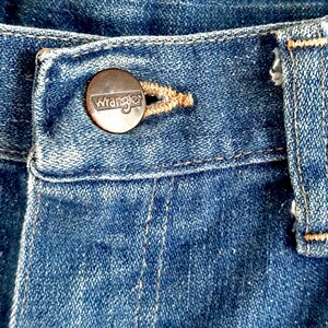Vintage Wrangler Jeans With Sunburst Stitching and Boot Cut Silhouette. vintage blue jeans. vintage wranglers. vintage sunburst jeans. vintage bell bottoms. vintage wrangler bells. vintage denim bell bottoms. vintage boot cut jeans. vintage boot cut wranglers. vintage boot cut denim. vintage boho jeans. vintage wearer wear. vintage rodeo jeans.