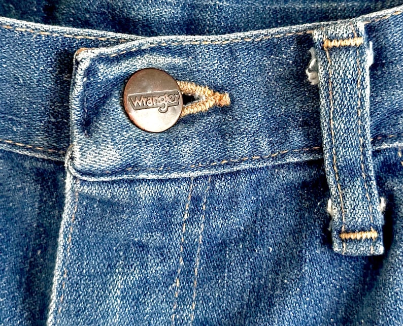 Vintage Wrangler Jeans With Sunburst Stitching and Boot Cut Silhouette. vintage blue jeans. vintage wranglers. vintage sunburst jeans. vintage bell bottoms. vintage wrangler bells. vintage denim bell bottoms. vintage boot cut jeans. vintage boot cut wranglers. vintage boot cut denim. vintage boho jeans. vintage wearer wear. vintage rodeo jeans.