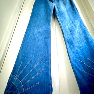 Vintage Wrangler Jeans With Sunburst Stitching and Boot Cut Silhouette. vintage blue jeans. vintage wranglers. vintage sunburst jeans. vintage bell bottoms. vintage wrangler bells. vintage denim bell bottoms. vintage boot cut jeans. vintage boot cut wranglers. vintage boot cut denim. vintage boho jeans. vintage wearer wear. vintage rodeo jeans.