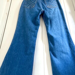 Vintage Wrangler Jeans With Sunburst Stitching and Boot Cut Silhouette. vintage blue jeans. vintage wranglers. vintage sunburst jeans. vintage bell bottoms. vintage wrangler bells. vintage denim bell bottoms. vintage boot cut jeans. vintage boot cut wranglers. vintage boot cut denim. vintage boho jeans. vintage wearer wear. vintage rodeo jeans.