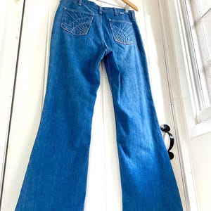 Vintage Wrangler Jeans With Sunburst Stitching and Boot Cut Silhouette. vintage blue jeans. vintage wranglers. vintage sunburst jeans. vintage bell bottoms. vintage wrangler bells. vintage denim bell bottoms. vintage boot cut jeans. vintage boot cut wranglers. vintage boot cut denim. vintage boho jeans. vintage wearer wear. vintage rodeo jeans.