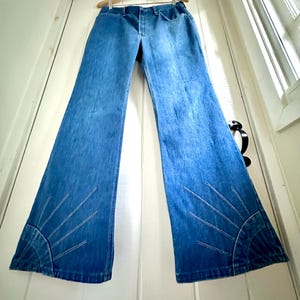 Vintage Wrangler Jeans With Sunburst Stitching and Boot Cut Silhouette. vintage blue jeans. vintage wranglers. vintage sunburst jeans. vintage bell bottoms. vintage wrangler bells. vintage denim bell bottoms. vintage boot cut jeans. vintage boot cut wranglers. vintage boot cut denim. vintage boho jeans. vintage wearer wear. vintage rodeo jeans.