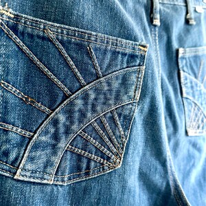 Vintage Wrangler Jeans With Sunburst Stitching and Boot Cut Silhouette. vintage blue jeans. vintage wranglers. vintage sunburst jeans. vintage bell bottoms. vintage wrangler bells. vintage denim bell bottoms. vintage boot cut jeans. vintage boot cut wranglers. vintage boot cut denim. vintage boho jeans. vintage wearer wear. vintage rodeo jeans.