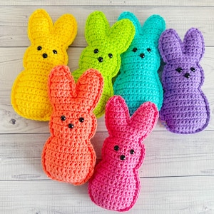 Può includere: Una collezione di sei coniglietti all'uncinetto fatti a mano in vari colori: giallo, verde, turchese, viola, arancione e rosa. Ogni coniglietto ha occhi di perline nere e una classica forma di marshmallow. Perfetto per Pasqua.