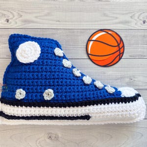 Puede incluir: Un zapato de crochet azul con detalles blancos y una suela blanca y negra, junto a una pelota de baloncesto naranja.