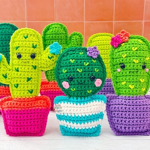 May include: A collection of handmade crochet cactus plants in various colors. The cacti are green with smiling faces and small flower accents. Each cactus sits in a colorful pot, with options including pink, orange, blue, and purple.