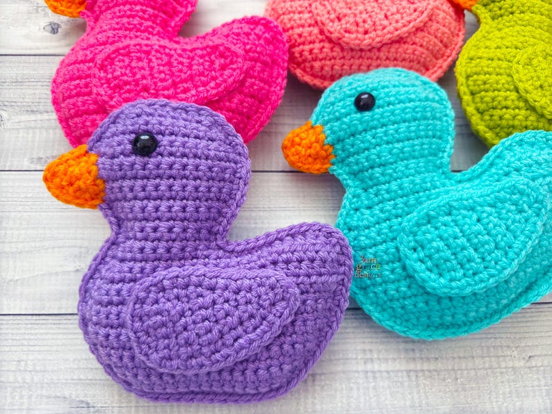 Peut inclure: Cinq canards en crochet de diff&eacute;rentes couleurs&nbsp;: violet, rose, turquoise, vert et orange. Les canards sont tous tourn&eacute;s dans la m&ecirc;me direction et sont dispos&eacute;s en demi-cercle.