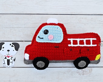 May include: A red crocheted fire truck toy with a blue windshield, white ladder, and black wheels. The truck has a smiling face with a black eye, a pink cheek, and a white light on top.