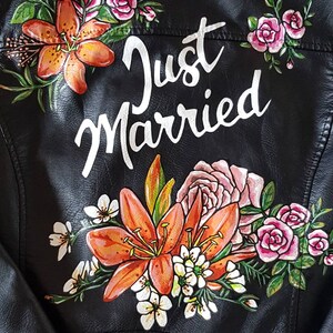 May include: Black leather jacket with a floral design and the words "Just Married" painted on the back.