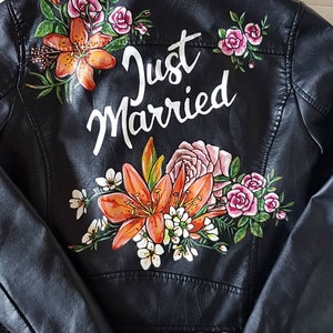 May include: Black leather jacket with a floral design and the words "Just Married" painted on the back.