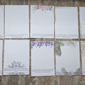 May include: Ten blank cards with different floral designs and inspirational quotes. The cards are white with a light blue, purple, green, or yellow floral design in the corner. Each card has a different quote from the Bible.