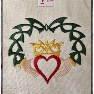 May include: Embroidered design of a Celtic knot heart with a crown above it, surrounded by a green Celtic knot. The heart is red, the crown is gold, and the knots are green.