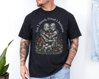 Puede incluir: Camiseta negra con un gráfico de dos caballeros con armadura abrazándose entre flores. El diseño incluye el texto "Out I Stand, Proud I Remayne" en un arco circular. Los caballeros visten armaduras plateadas y rojas.