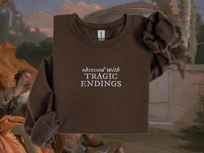a brown sweatshirt with the text "obsessed with TRagic Endings" printed on it.