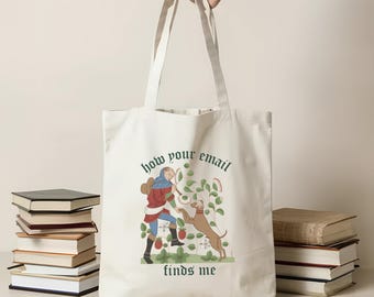 May include: Cream-colored tote bag with a medieval-style illustration of a person and a dog. The illustration is in shades of red, blue, and brown. The text "how your email finds me" is printed on the bag in green.