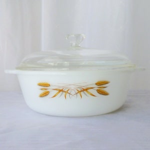 May include: White casserole dish with a clear glass lid. The dish features a wheat stalk design in shades of gold and brown. The dish has two small handles and a clear glass knob on the lid.