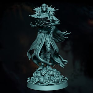 Puede incluir: Una figura de color turquesa de una figura vestida con una túnica que sostiene un libro, de pie sobre una pila de calaveras y huesos. La figura tiene una cara esquelética y una capa dramática. La figura está sobre una base redonda.