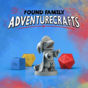 May include: A grey figurine of a frog-like character in a hat and cloak, with the text "FOUND FAMILY ADVENTURECRAFTS" above. Three colourful dice are in the background: blue, yellow, and red. The background is a gradient of blue, red, and yellow.