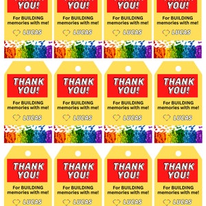 Könnte beinhalten: Zwölf gelbe Geschenkanhänger mit roter und weißer Aufschrift "Danke!" und "Für das Bauen von Erinnerungen mit mir!" mit einem Herz und dem Namen "Lucas". Die Anhänger haben einen regenbogenfarbenen Hintergrund aus kleinen Plastikbausteinen.
