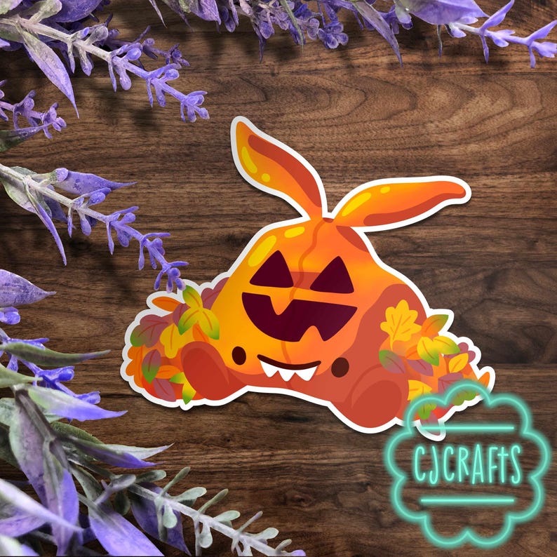 Puede incluir: Una pegatina con una calabaza de dibujos animados con orejas de conejo, una cara tallada y hojas de oto&ntilde;o. La pegatina tiene un borde blanco y el texto "CJ CRAFTS" en una burbuja turquesa.