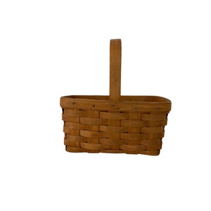 May include: A small, rectangular, brown wicker basket with a single wooden handle.