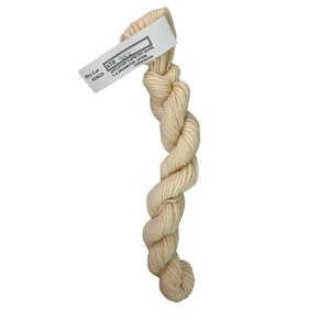 May include: A skein of off-white yarn, tightly twisted into a rope-like form. A white tag is attached, bearing the text "ATH 382" and other details. The yarn appears soft and is suitable for various crafting projects.