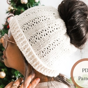 Può includere: Cappello bianco all'uncinetto con un foro nella parte superiore per uno chignon. Il cappello è realizzato con un delicato motivo a punto e ha un bordo ripiegato. Il testo "PDF Pattern" è visibile nell'immagine.