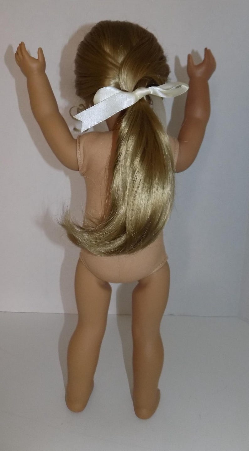 K&ouml;nnte beinhalten: Puppe mit blondem Haar, das zu einem Pferdeschwanz gebunden ist, der mit einem wei&szlig;en Band befestigt ist. Die Puppe tr&auml;gt einen hautfarbenen Body. Die Arme der Puppe sind erhoben und die Beine gerade.