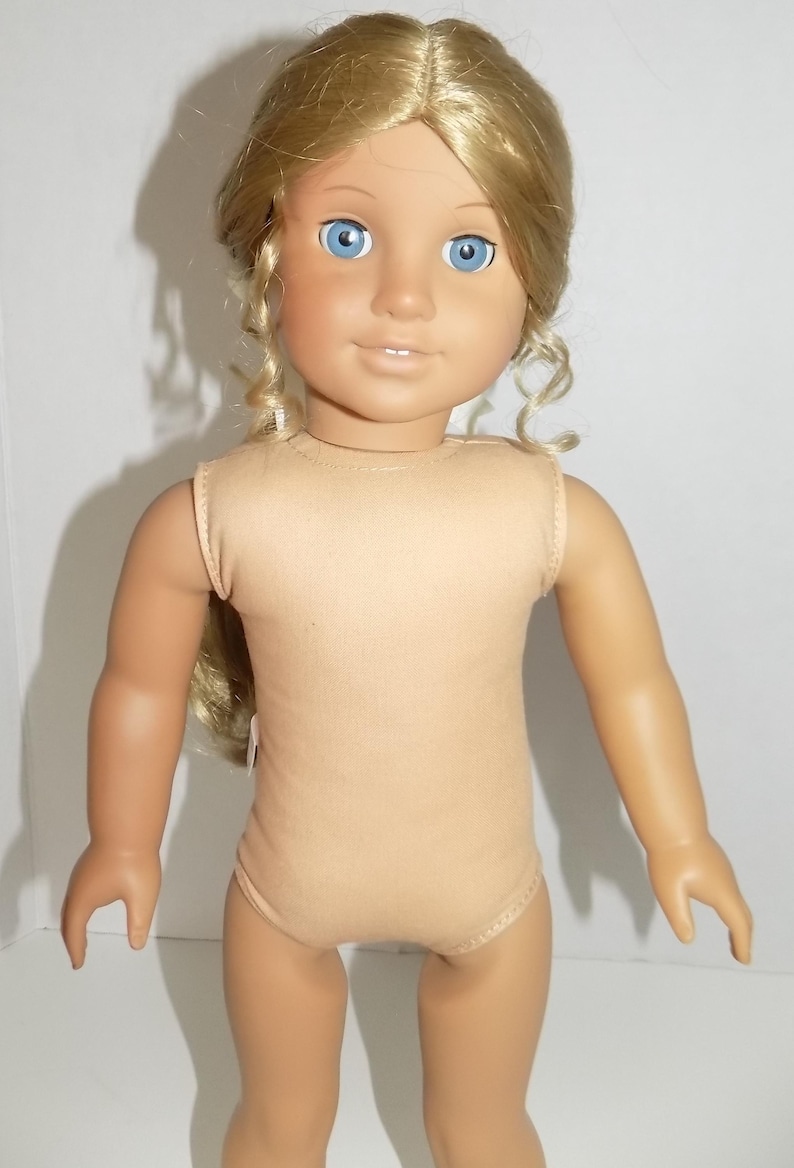 K&ouml;nnte beinhalten: Puppe mit blondem Haar, das in lockeren Locken gestylt ist, und blauen Augen. Die Puppe tr&auml;gt einen beigefarbenen Body. Der Hautton der Puppe ist hell. Die Puppe steht vor einem wei&szlig;en Hintergrund.