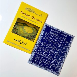 May include: A yellow and blue book set for learning the Arabic alphabet. The book on the left is titled "Nurani Qa'idah" with the text "With Tajweed Rules in English and Urdu". The book on the right is a blue chart with the Arabic alphabet and the transliteration in English.
